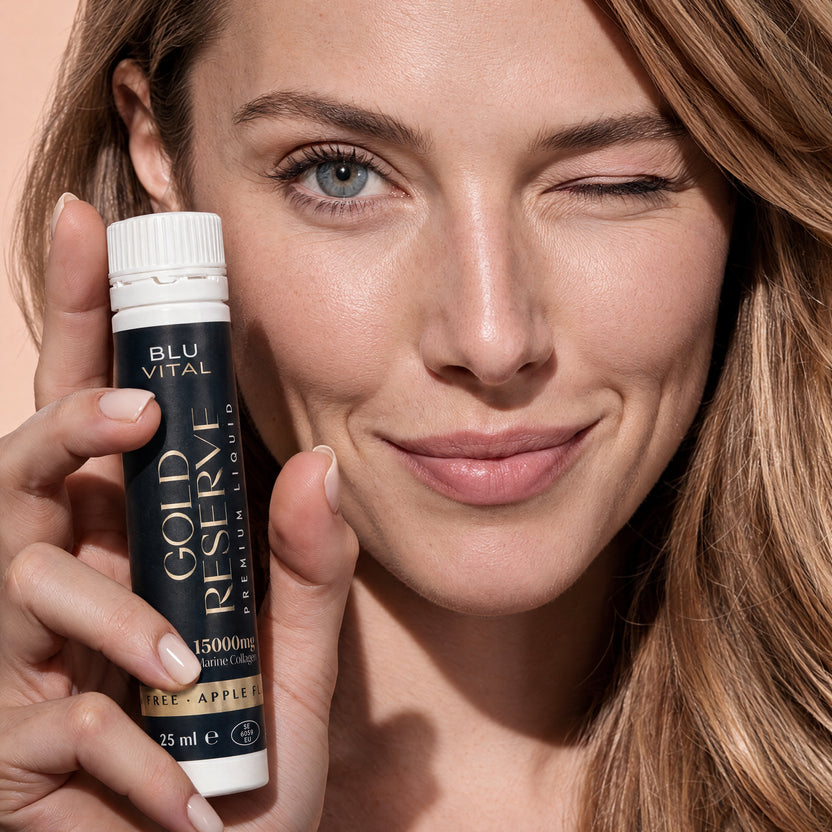 Knipogende vrouw met een BLUVITAL The Gold Reserve-collageenshot van 25 ml naast haar gezicht.